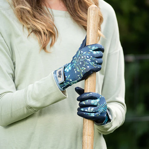 person wearing nitrile garden gloves holding a broom